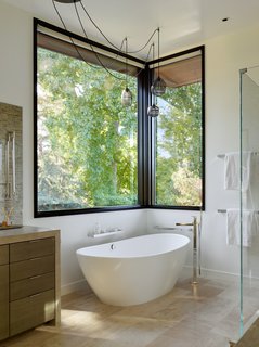A standalone soaking tub by MTI Baths offers respite at the end of a long day. Adding to the zen-like ambiance are Tatami Wheat limestone flooring and Sea Grass Antique limestone counters, both by Walker Zanger.