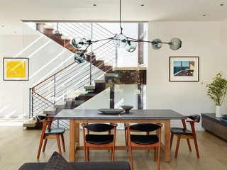 The formal dining area pairs a custom table by Heerenhuis Manufactuur with vintage Danish midcentury chairs. A Branching Chandelier by Lindsey Adelman in oil rubbed bronze with gray, glass globes hangs above the scene.