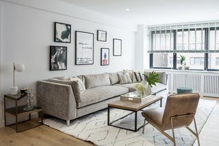 A NYC living room apartment features framed art hung salon-style and pops of greenery.