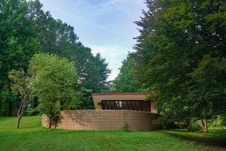 A curved concrete block wall conceals one of the three exterior terraces. Low-slung roofs appear to hover above the landscape.