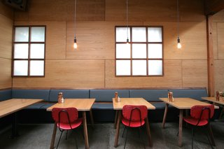 Red chairs lend a pop of color against rich oak walls and walnut-and-leather banquets. 