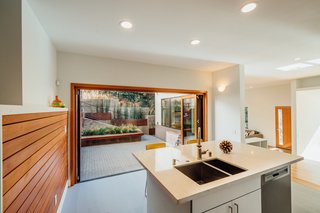 8 Things to Consider When Choosing Retractable Glass Walls - Photo 13 of 15 - Aluminum Wood provides warmth to this modern, clean-lined kitchen.