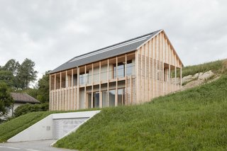 A Minimalist Home Is Built Into Steep Terrain in an Austrian Valley - Photo 1 of 13 - To help blend the building into the landscape, the sections of the home visible above the slope are cladded in natural and unfinished spruce sourced from the owner's own forest. 