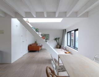 An Architect Creates a Two-Level Houseboat For His Family on a Tight Budget - Photo 6 of 10 - An open staircase seamlessly separates the living area from the dining room and kitchen. The stairs lead to the deck allows, which is decorated with plants and partly covered by solar panels that power the home.
