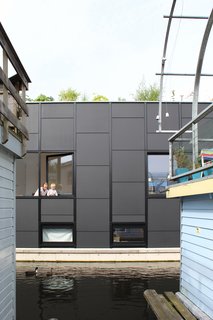 An Architect Creates a Two-Level Houseboat For His Family on a Tight Budget - Photo 3 of 10 - The tatami-inspired grid layout also influenced the exterior cladding with its dark offset panels that subtly reference the color of the water below the home.
