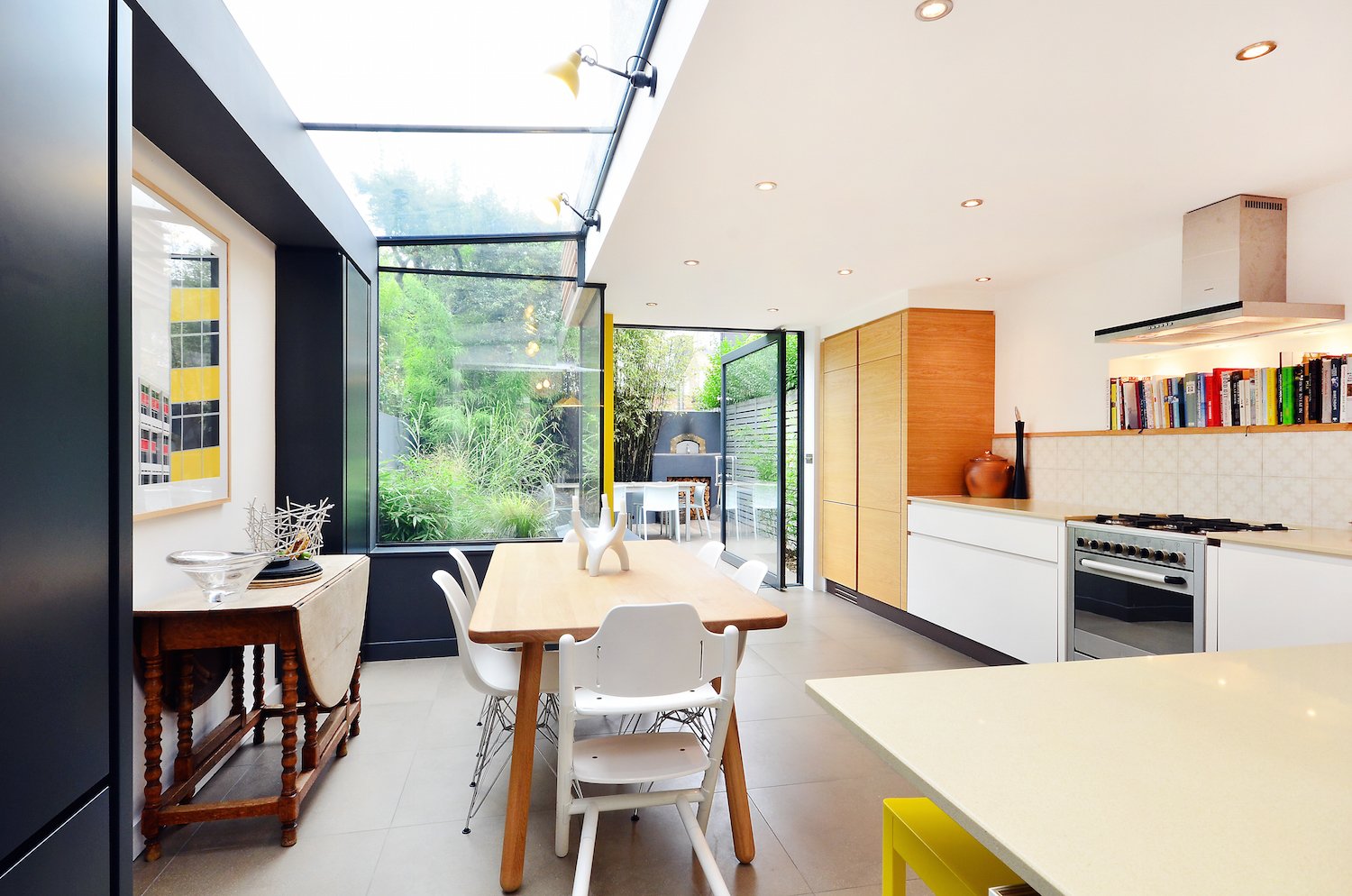 The oak dining table and its Eames DSR side chairs are placed in the glass-enclosed side return.