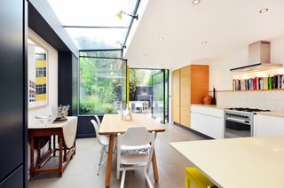 The oak dining table and Eames DSR side chairs are placed in the glass-enclosed side return.