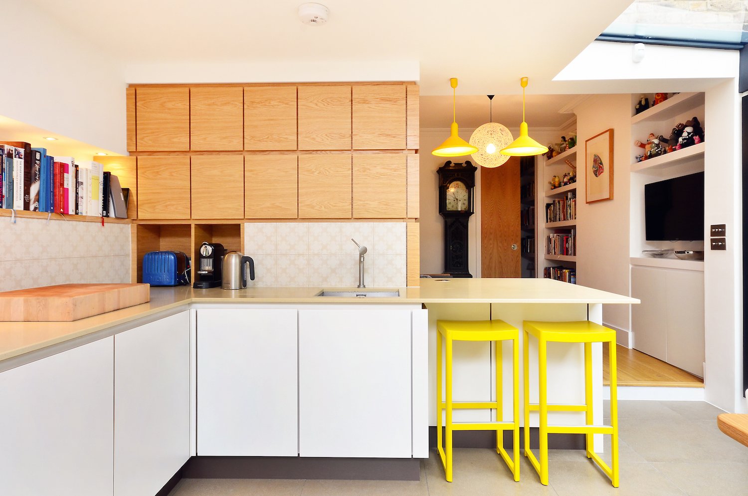 Bright yellow Torch S3 large cone pendant lights and Seleri bar stools reinforce the black-and-yellow color palette.