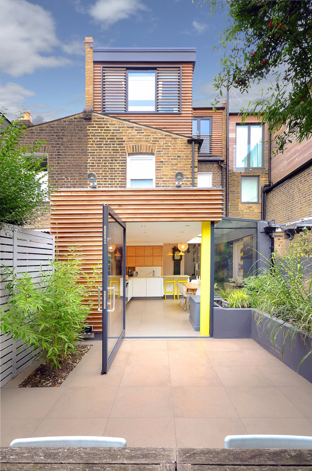 The new additions of the home are clad in bespoke cedar profiles that inject a modern flair to the 20th-century brick building.