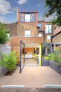 The new additions of the home are clad in bespoke cedar profiles that inject a modern flair to the 20th-century brick building.