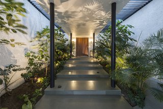 Uplights accent the lush landscaping flanking the entrance.
