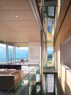 Mirrored panels clad the ceiling above this textured axis—from the outdoor water feature to the interior stone paving—to emphasize the axis and reflect the moment of sunlight, water, and people.