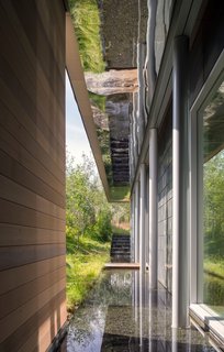 Located between the courtyard and the home, the shallow linear pool on the north-south axis is reflected by mirrored-finish panels.