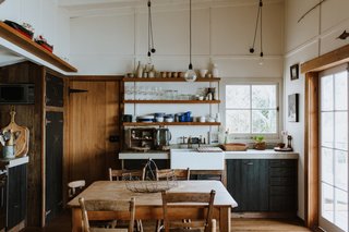 Two French doors open up the open-plan kitchen and dining area to a covered outdoor terrace overlooking the water.