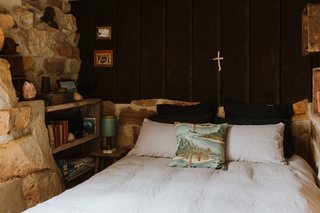 The second bedroom, located on a lower level, includes a handmade queen bed nestled between walls that have been built from original sandstone and lined with timber.