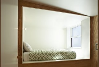 The white-walled kitchen and sleeping areas are cut out from plywood modules.