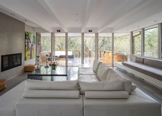 The living room is located in the north wing and has a wood-burning fireplace, built-in sofa, and moveable walls of glass.