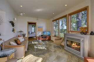 The cozy living room with a fireplace connects to the master bedroom beyond.