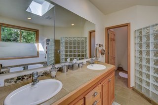 A peek inside the master bathroom with a double vanity and glass block shower.