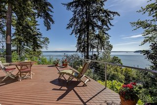 French doors on the upper floor open up to a 1,000-square-foot outdoor deck that overlooks views of the water, mountains, and islands beyond.