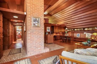 The foyer, marked by brick paving, leads to a hallway to the left and the great room to the right.
