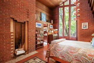 The master bedroom includes a brick fireplace, a 25-foot-tall ceiling, and doors that lead outside.