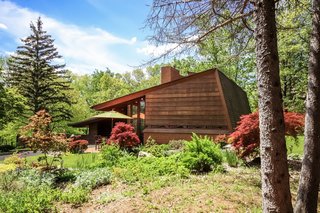Shielded from the street, the two-bedroom, two-bath home is set on a 10-acre property with gardens, lawns, and old-growth trees overlooking Honey Creek.