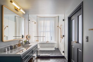 The luxurious Publisher Suite bath features a free-standing bathtub next to a large window with a privacy curtain.