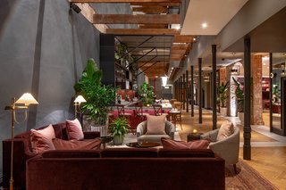 The 60-foot-high atrium floods the lobby and Press Room bar with natural light, while lush plantings and a Havwoods parquet flooring soften the original exposed and slate-colored plaster walls.