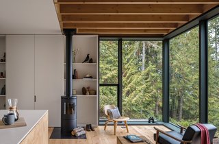 Light timber floors, white-painted MDF shelving and cabinets, as well as black metal accents, give the home a clean and contemporary appearance.