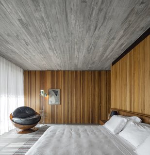 The interiors feature a minimal palette of timber and concrete. The bathroom of this bedroom is hidden behind a sliding wall.