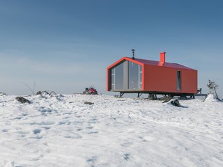 The prefab cabin is elevated atop six metal pillars to minimize site impact.