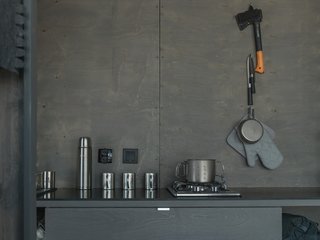 The simple kitchen consists of a sink, countertop, dishes, and a two-burner stove.