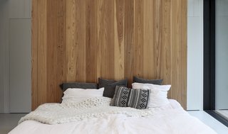 A timber wall imbues warmth into the minimalist bedroom.