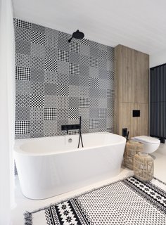 Black accents and patterns breath life into the bathroom with a freestanding tub.
