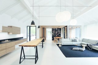 The open-plan living room, kitchen, and dining area are handsomely punctuated with Lightyears Caravaggio pendant lights and the dramatic Moooi Random Lights.