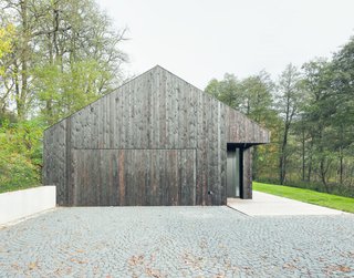 The home is accessed from the west, where the garage is hidden behind a charred timber door.