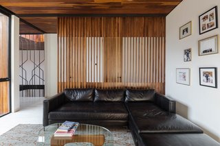 The upper-level family room is furnished with a simple black sectional and a Noguchi table.
