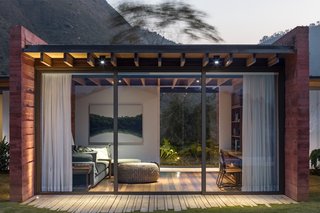 Glazing on both sides gives the television room an airy, pavilion-like feel.