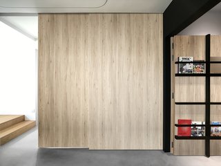 Top-mounted sliding timber doors close the guest room off from the living room for privacy. When not in use, the sliding doors stack flush against the right wall. 