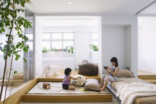 The guest room features two concealed beds: a wall-bed stored upright and a pull-out bed beneath the indoor garden's raised timber deck. For privacy, the architects have added sliding wooden doors, as well as privacy curtains that can be drawn along a curved track that is recessed into the false ceiling.