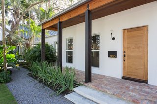 The existing home has been painted a crisp white, while timber elements and brick flooring lend warmth to the space.