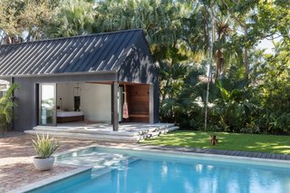 The master bedroom's sliding glass doors open up to an outdoor terrace, garden, and the pool.