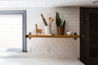Handcrafted clay subway tiles line one side of the kitchen. Brentwood Builders custom built the open shelving, fitted with TrueNorth Metalworks brackets.