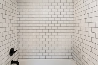 Subway tile surrounds the bathtub in the second bathroom.
