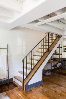 Previously located in the kitchen, the staircase was moved to the space opposite the dining area, and was opened up with a delicate metal railing.
