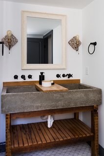 The double vanity in the master bath has a concrete trough sink with a wood slab counter.