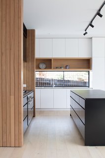The white kitchen cabinetry is by Nikpol. The sink is integrated into a stainless steel benchtop.