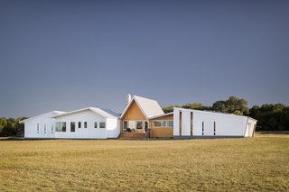 "Working within the restrictive budget, design was not sacrificed; rather, it inspired the team to find a vocabulary that was simple yet refined," adds the firm. "The exterior of the home is defined by clean lines, a sculptural gable roof, and a contrasting material palette of corrugated-aluminum and warm, locally sourced cypress. "