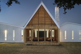 "The porch’s distinctive 30-foot peak is discernible from a great distance, and its rhythmic, horizontal cypress slats are a contemporary interpretation of traditional vented gables," add the architects.